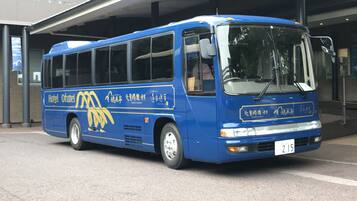 A blue bus with the text "Hotel Ofutai" and Chinese characters, parked at a bus stop.