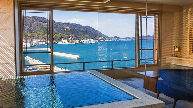 A modern interior with a large window overlooking a coastal view, a pool, and a seating area. - Hotel Ofutei (Fukuyama)