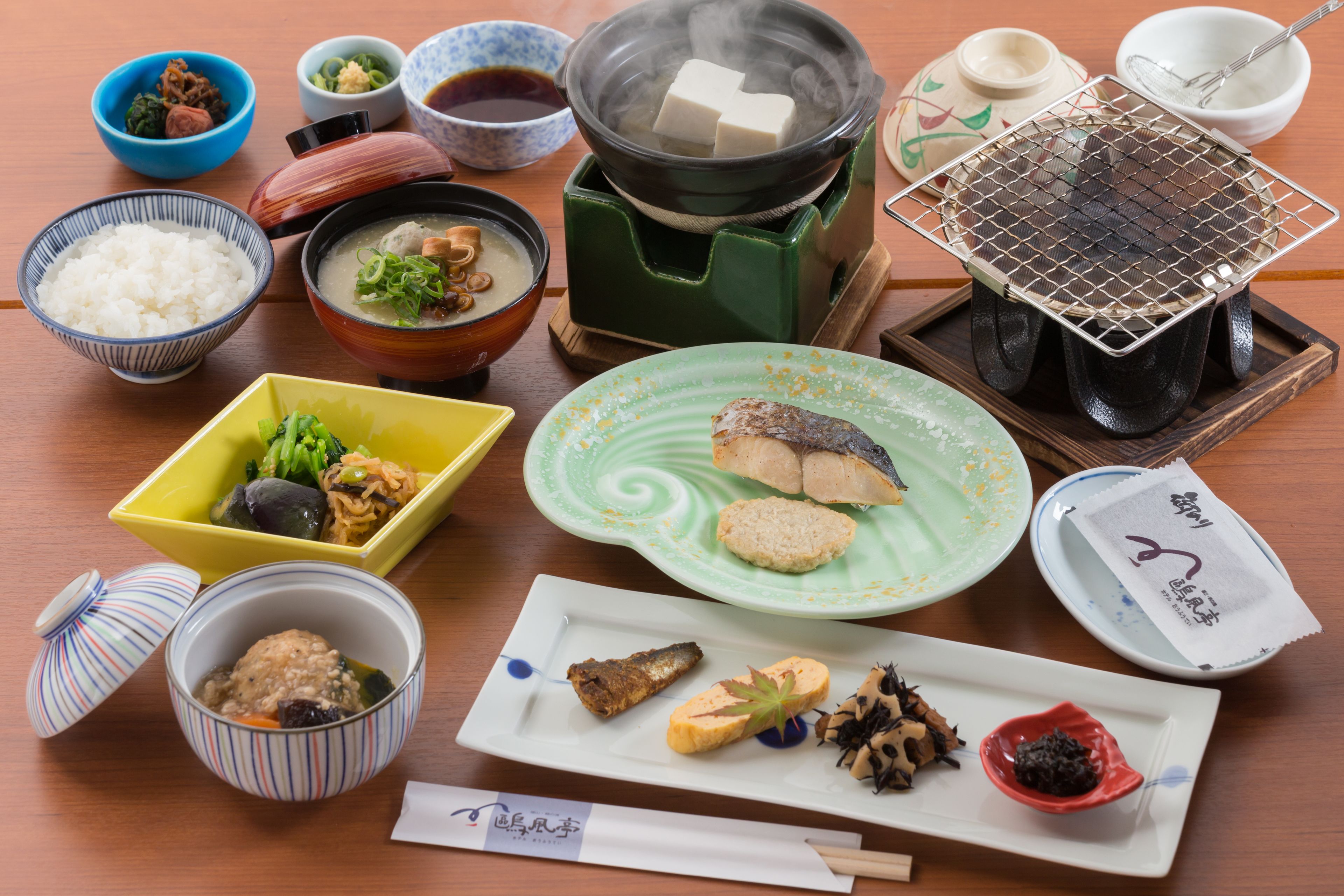 Diversos platos japoneses, como sushi, arroz y sopa, dispuestos sobre una mesa de madera.