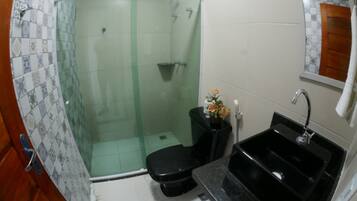 A bathroom with a glass-enclosed shower, a black toilet, a sink, and a mirror.