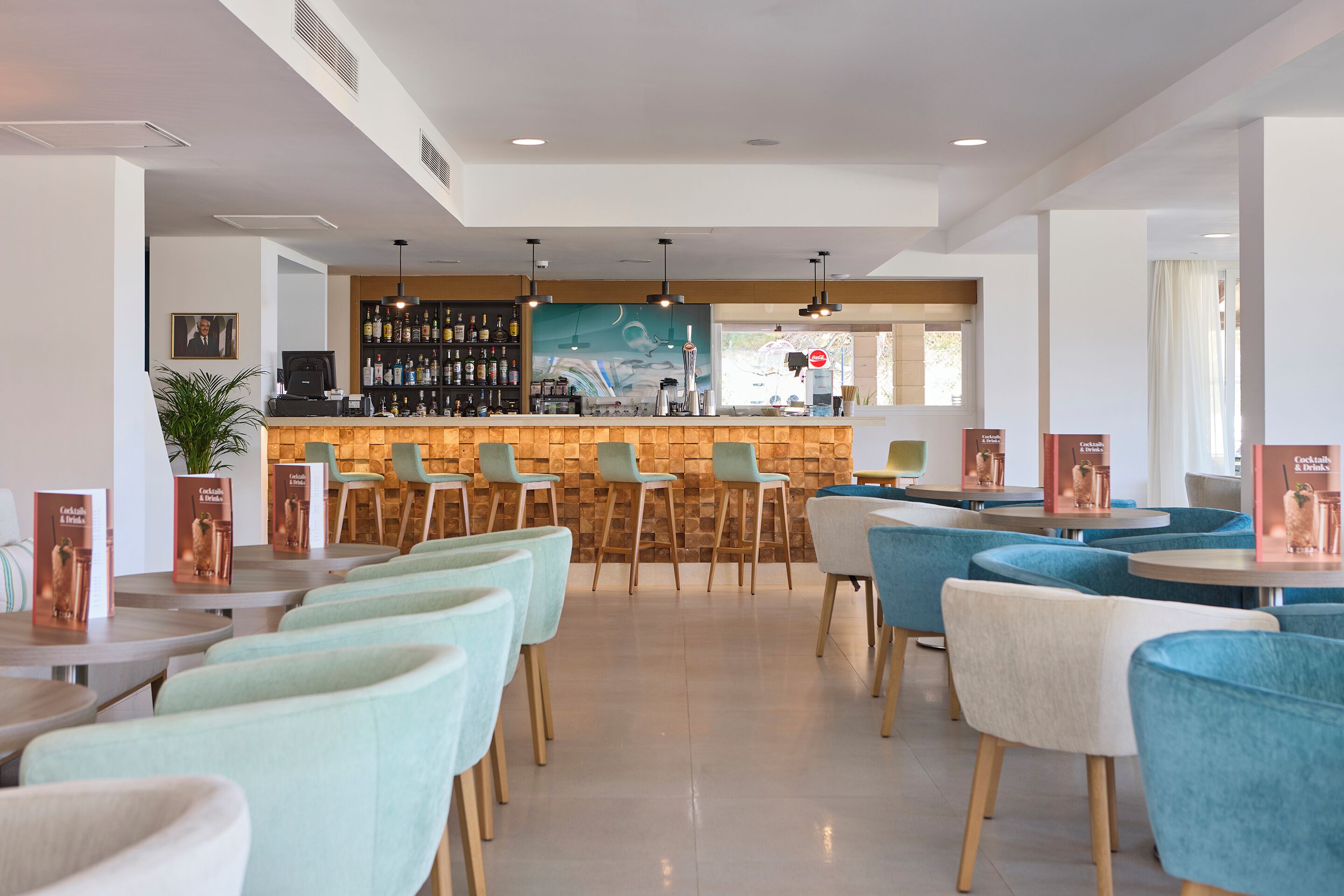 A modern bar area with a counter, seating, and a mural.