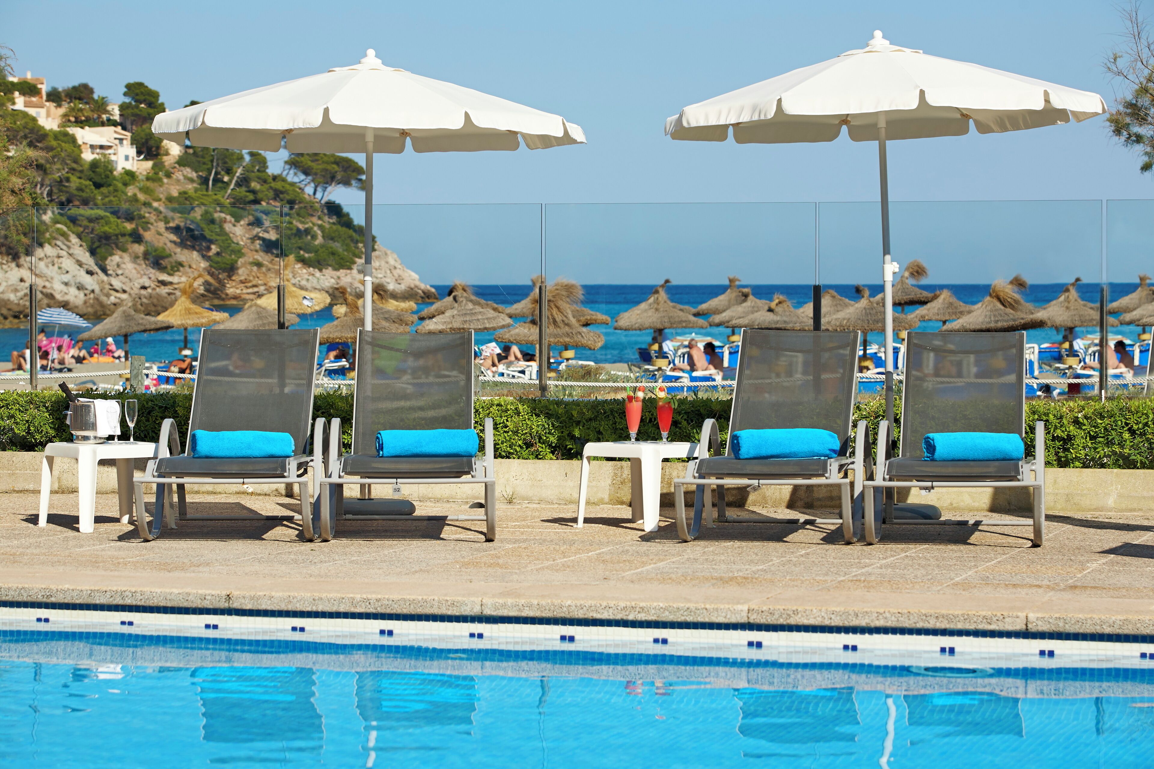 Una piscina al aire libre, sombrillas, tumbonas