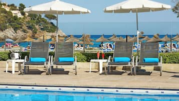 Una piscina al aire libre, sombrillas, tumbonas