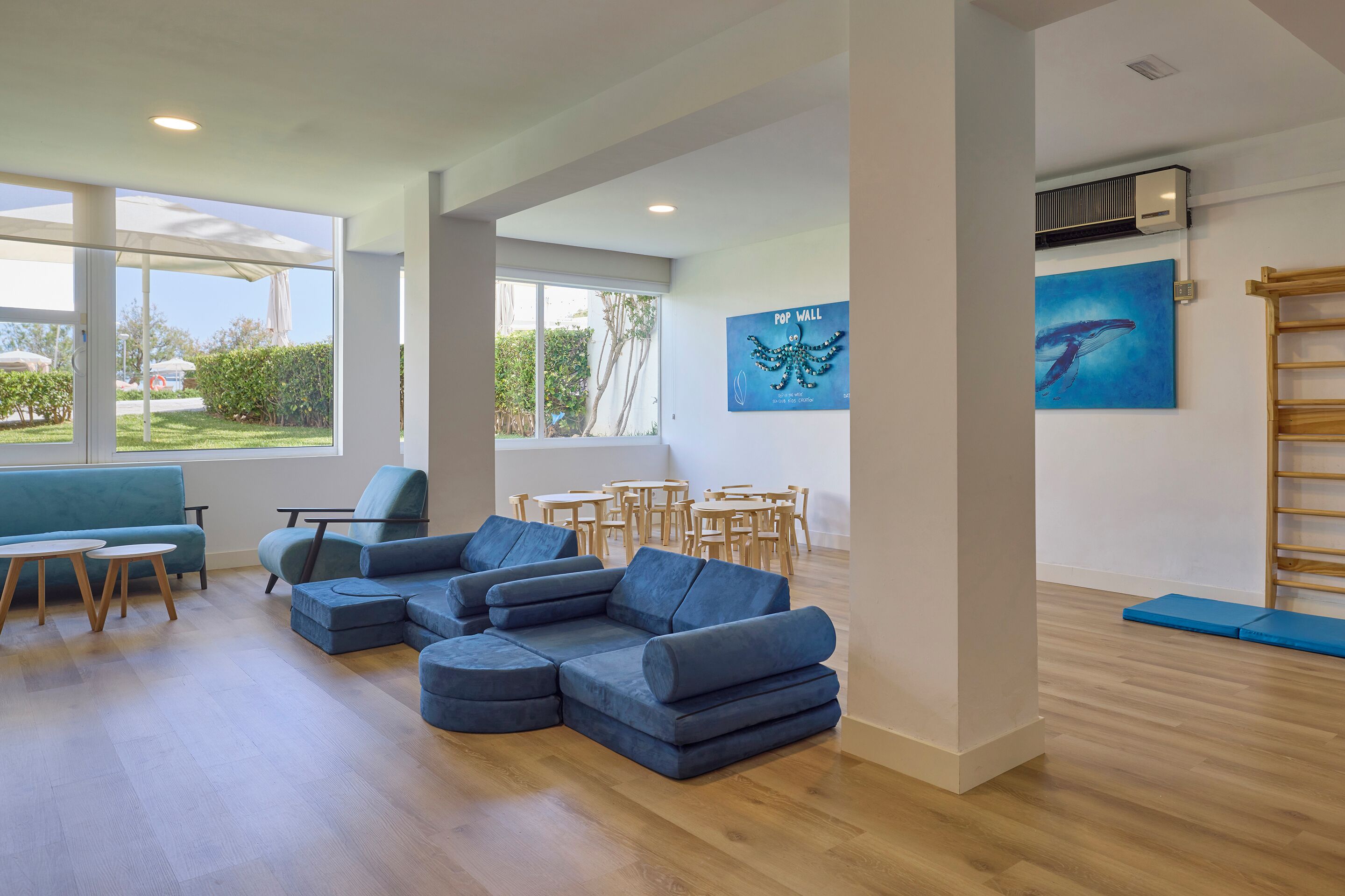 A spacious room with a sectional sofa, a dining area, and artwork on the walls.