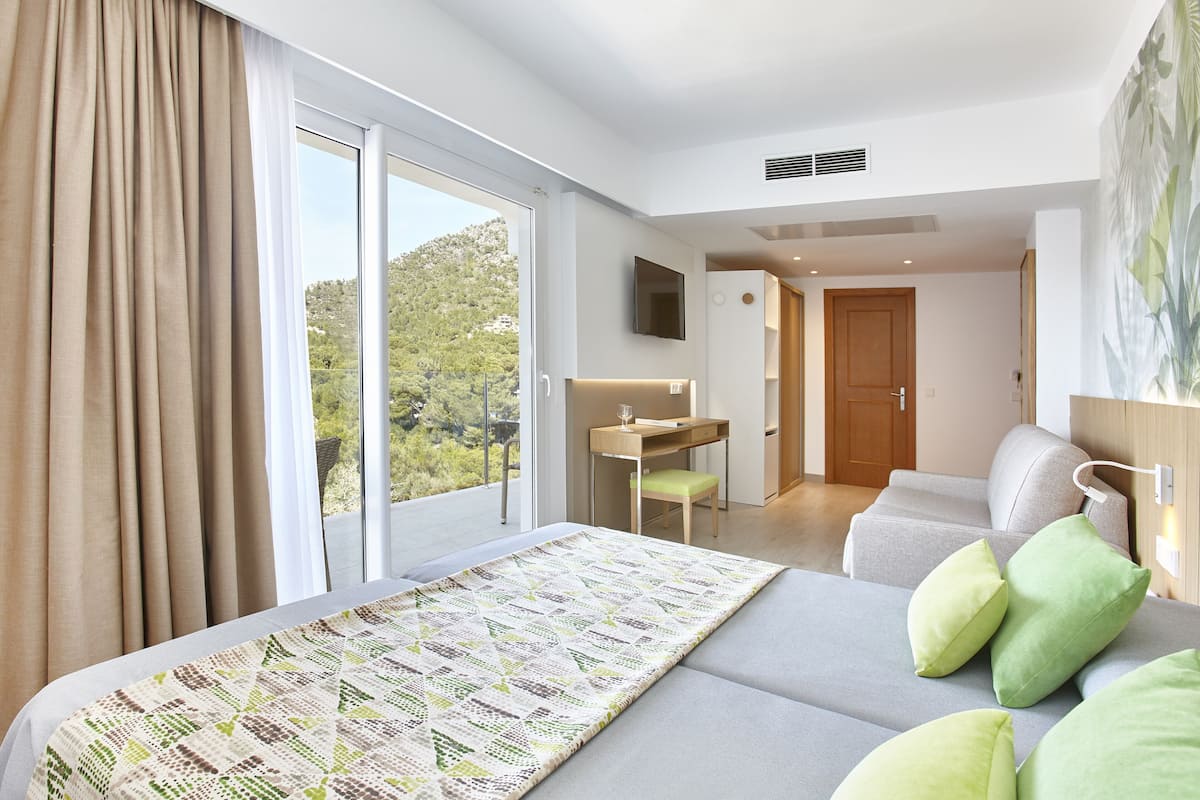 A hotel room with a large bed, a desk, a chair, and a view of the outdoors.