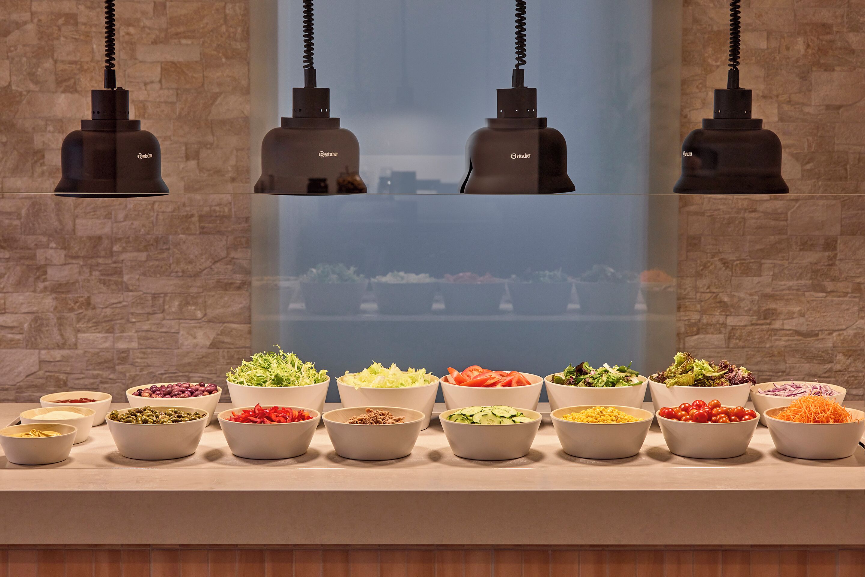 A buffet with various food items and three pendant lights.