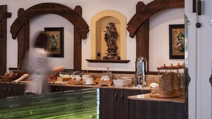 A kitchen with wooden beams, a statue, and various kitchen items. - Alpenhotel Fernau (Neustift Im Stubaital)