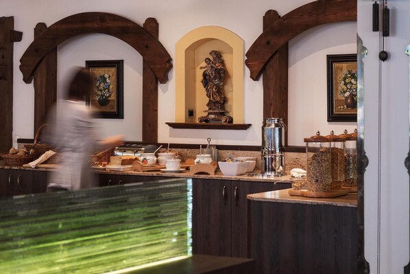 A kitchen with wooden beams, a statue, and various kitchen items. - Alpenhotel Fernau (Neustift Im Stubaital)