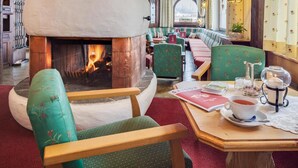 A cozy restaurant with a fireplace, wooden furniture, and a table with a cup of tea. - Alpenhotel Fernau (Neustift Im Stubaital)