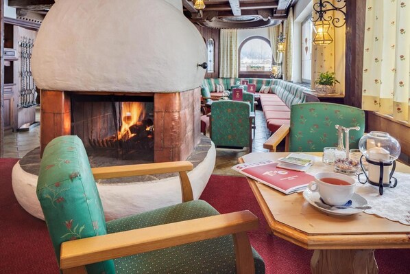 A cozy restaurant with a fireplace, wooden furniture, and a table with a cup of tea. - Alpenhotel Fernau (Neustift Im Stubaital)