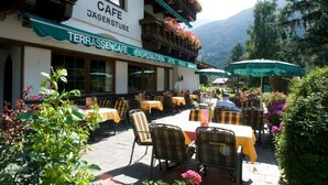 A cafe with outdoor seating, tables, and chairs, surrounded by greenery and mountains. - Alpenhotel Fernau (Neustift Im Stubaital)