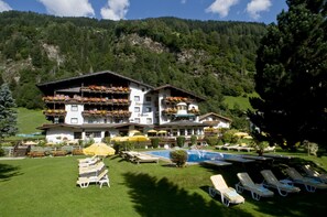 A hotel with a pool, sun loungers, and flower boxes on balconies. - Alpenhotel Fernau (Neustift Im Stubaital)