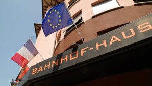 A building with a sign reading "BAHNHOF-HAUS" and flags of the European Union and France. - Bahnhof Haus (Chiasso)