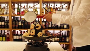 A person cooking shrimp on a pan over a stove. - Bahnhof Haus (Chiasso)