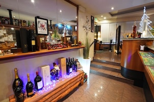 Un hall d’hôtel avec un comptoir d’accueil, un sapin de Noël et une présentation de bouteilles de vin.