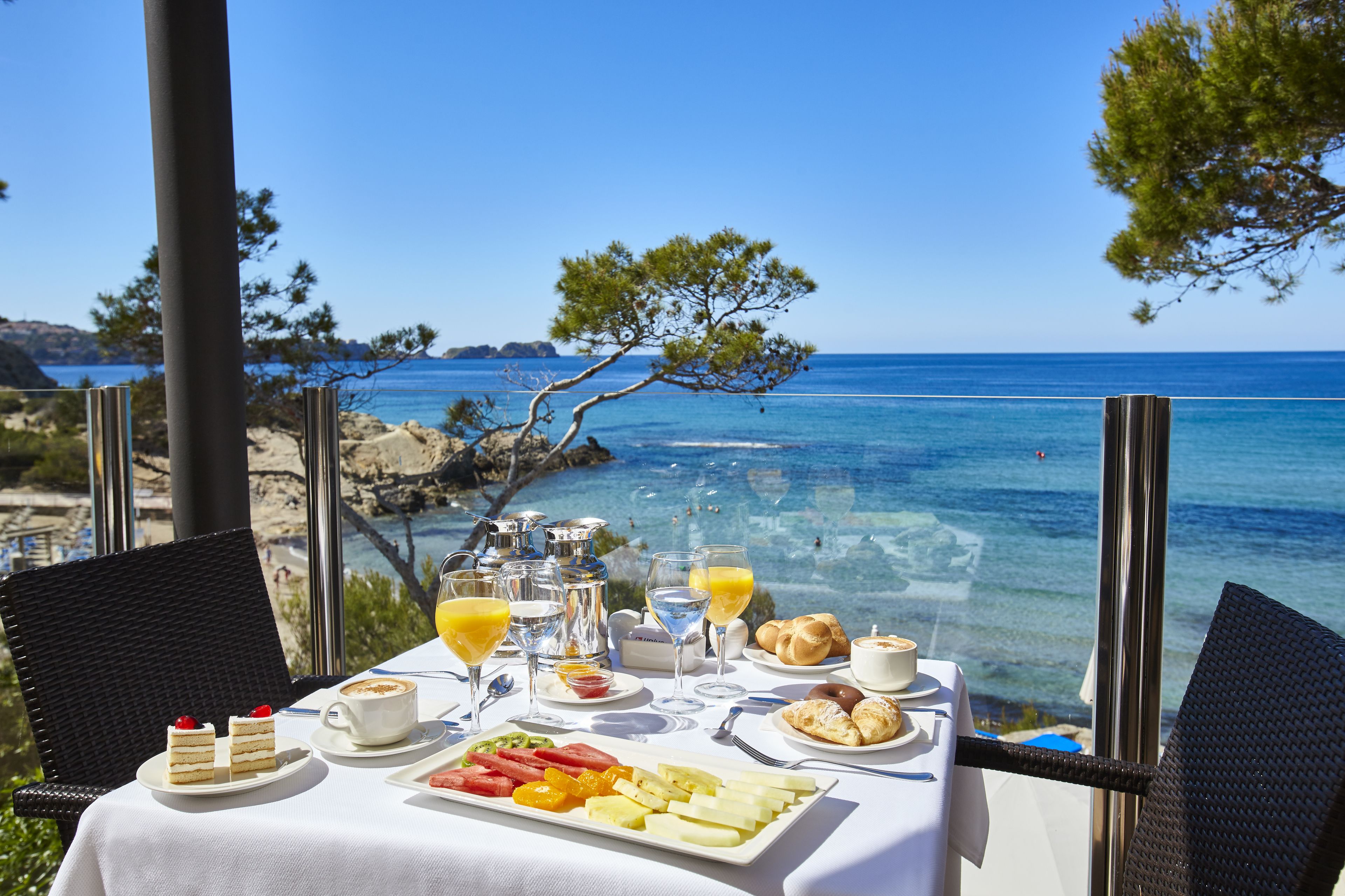 A table set with breakfast items and a view of the sea. - Universal Hotel Lido Park & Spa (Calvia)