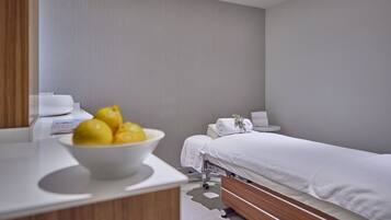 Un dormitorio moderno con una cama individual, una mesita de noche, un cuenco de limones y una pequeña mesa redonda con un bol blanco.