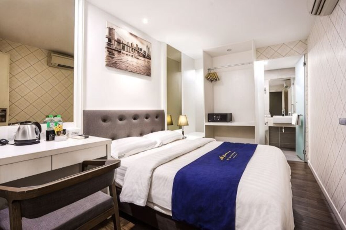 Een hotelkamer met een bed, een bureau, een stoel, een spiegel, een wastafel en een raam.