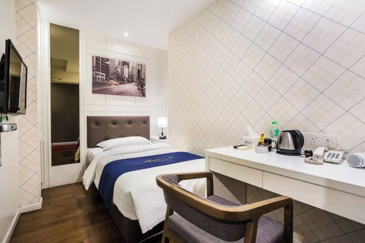 Een hotelkamer met een bed, een bureau, een stoel, een televisie en een foto aan de muur.