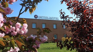 Un bâtiment d’hôtel avec une enseigne indiquant « INTER-HOTEL » et un ciel bleu clair en arrière-plan.