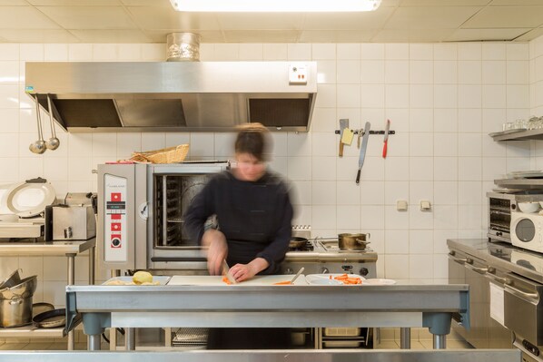 Una cocina con electrodomésticos de acero inoxidable, un horno grande y un chef preparando comida.