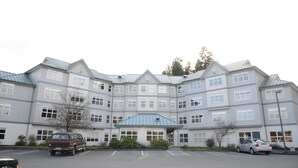 A large, multi-story building with a symmetrical facade, multiple windows, and a central entrance with a blue roof. - Quarterdeck Inn Port Hardy (Port Hardy)