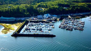 An aerial view of a marina with multiple docks and boats, surrounded by dense forest. - Quarterdeck Inn Port Hardy (Port Hardy)