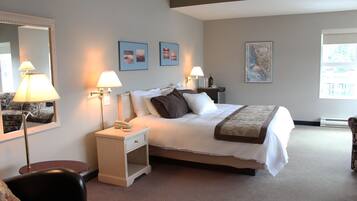 A neatly arranged hotel room with a bed, bedside lamps, a nightstand, a chair, and a large mirror.