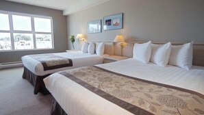 A hotel room with two beds, a large window, and a view of a snowy landscape. - Quarterdeck Inn Port Hardy (Port Hardy)