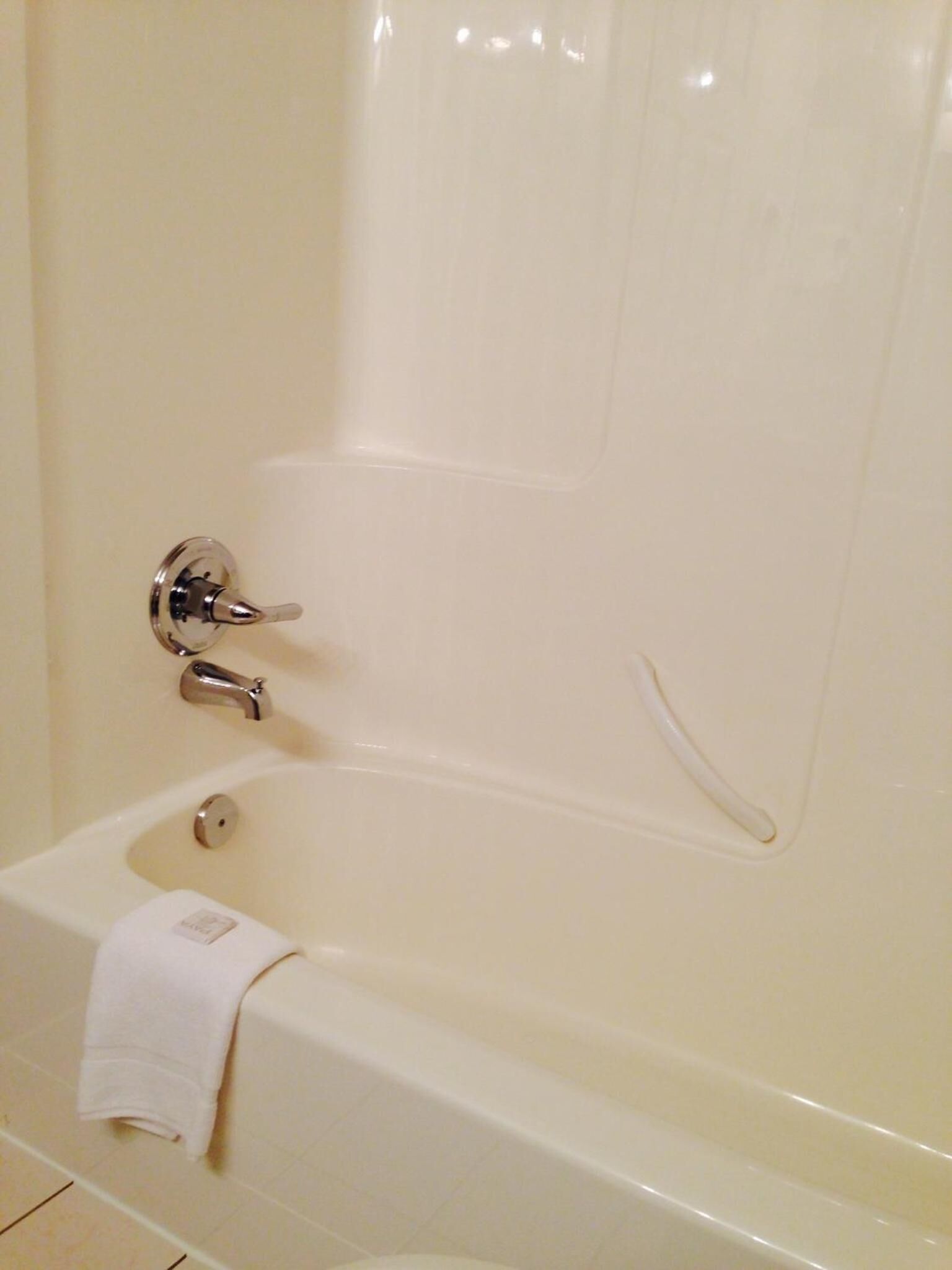 Une baignoire avec une serviette blanche, des robinets chromés et un sol carrelé.