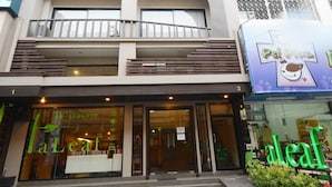 Un edificio de varios pisos con un llamativo logotipo de hoja verde en la fachada.