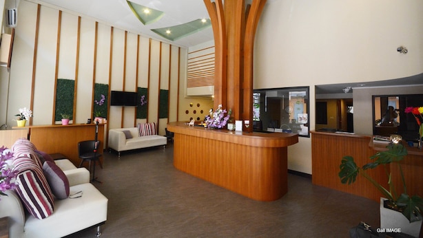 Un área de recepción moderna con un mostrador de madera, un sofá y una pantalla de televisión.
