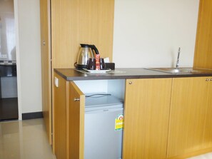A compact kitchen with a built-in refrigerator, a coffee maker, and a sink. - Aleaf Bangkok Hotel (Bangkok)