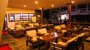 Un espace extérieur aménagé en terrasse, avec des meubles en bois, notamment des tables et des chaises, et une vue sur le restaurant intérieur.