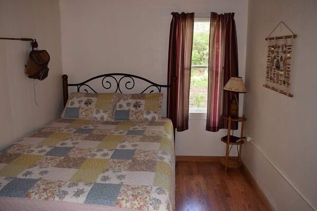 Un dormitorio con cama, cortinas, una lámpara de pared y un objeto decorativo.