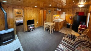 A cozy cabin interior with a wooden interior, a dining area, a kitchen, and a sleeping area. - Stoney River Lodge (Loveland)