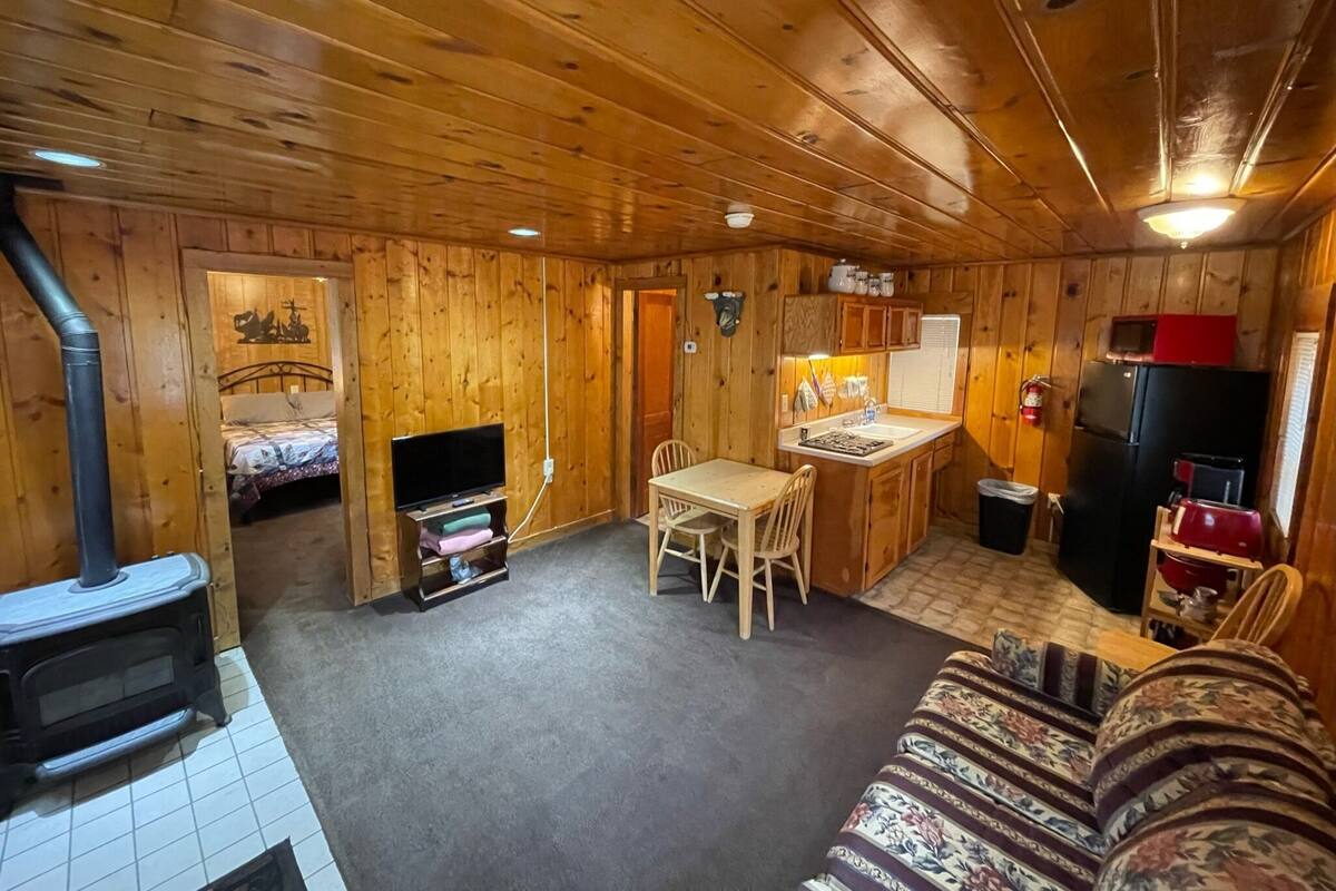 Un interior de cabaña acogedor, con detalles de madera, un comedor, una cocina y una zona de descanso.