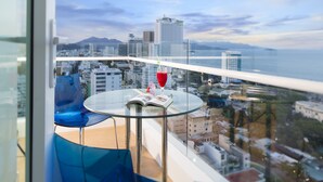 A balcony with a glass table, a blue chair, and a red drink. - Green World Nha Trang Apartment (Nha Trang)