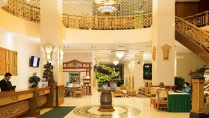 A grand lobby with a high ceiling, ornate chandeliers, and a central decorative column. - Green World Nha Trang Apartment (Nha Trang)