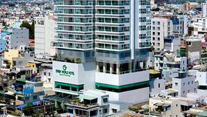 A tall hotel with multiple floors, balconies, and a prominent sign. - Green World Nha Trang Apartment (Nha Trang)