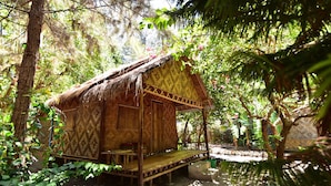 A rustic wooden hut with a thatched roof, surrounded by dense foliage and trees. - Green View Beach Resort (Koh Lipe)