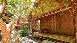 A rustic wooden building with a thatched roof, a bench, and a table with a basket. - Green View Beach Resort (Koh Lipe)