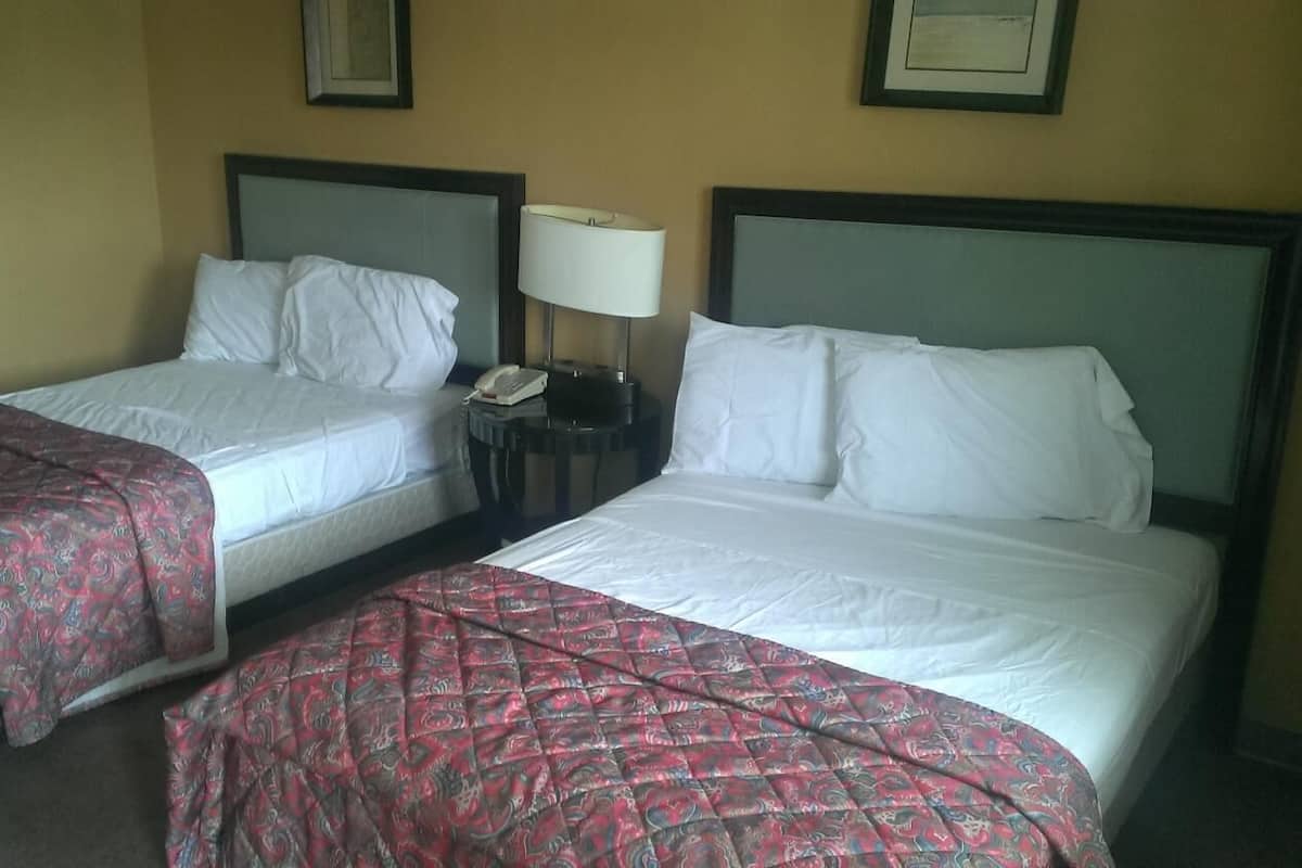 Two single beds with headboards, a bedside table with a lamp, and a telephone.