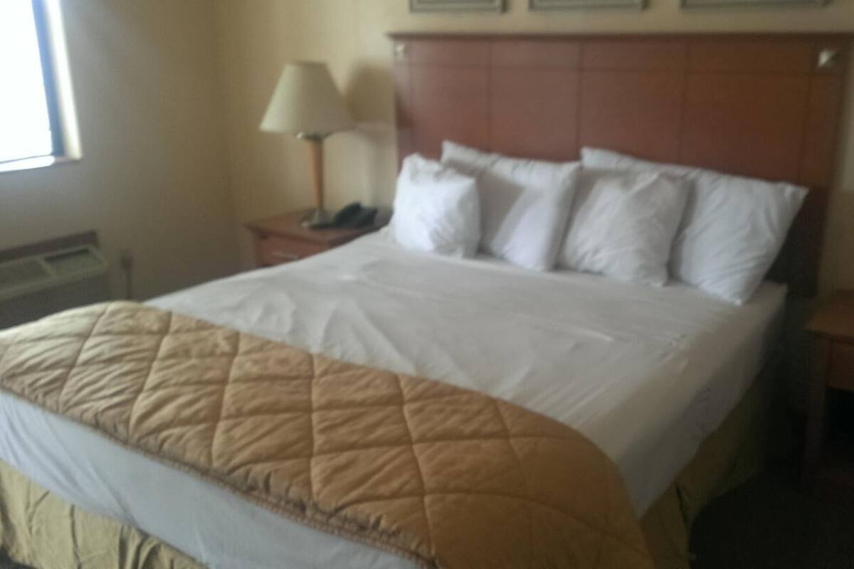 A neatly made bed with a quilted blanket, a wooden headboard, and two bedside lamps.