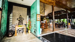 A reception area with a statue, a reception desk, and a seating area with tables and chairs. - Cocoville Phuket Resort (Chalong)