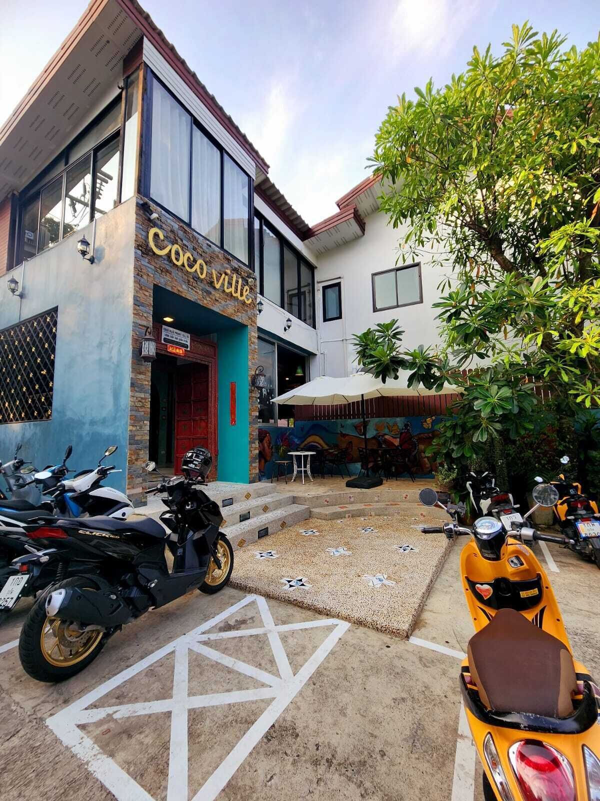 A building with a sign reading "CocoVille" and a parking area with motorcycles.