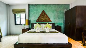 Uma cama bem arrumada em tons de verde e branco, com um adorno decorativo na parede acima e um guarda-roupa de madeira à direita.