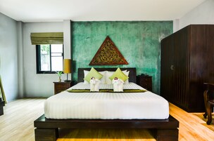 Uma cama bem arrumada em tons de verde e branco, com um adorno decorativo na parede acima e um guarda-roupa de madeira à direita.