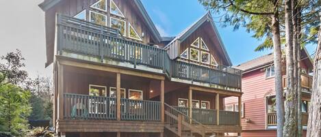 A multi-story wooden cabin with balconies, a deck, and a staircase.