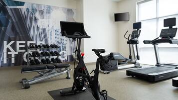A gym with cardio equipment, dumbbells, and a large motivational poster.